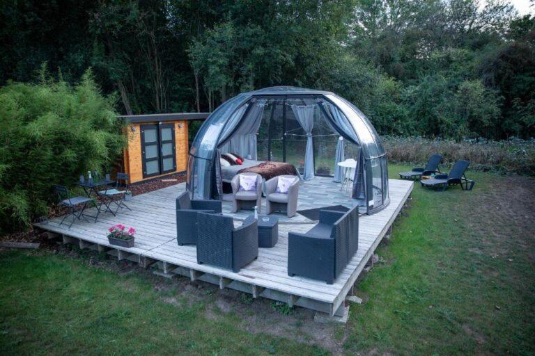 Bulle transparente romantique sur terrasse en bois entourée de verdure
