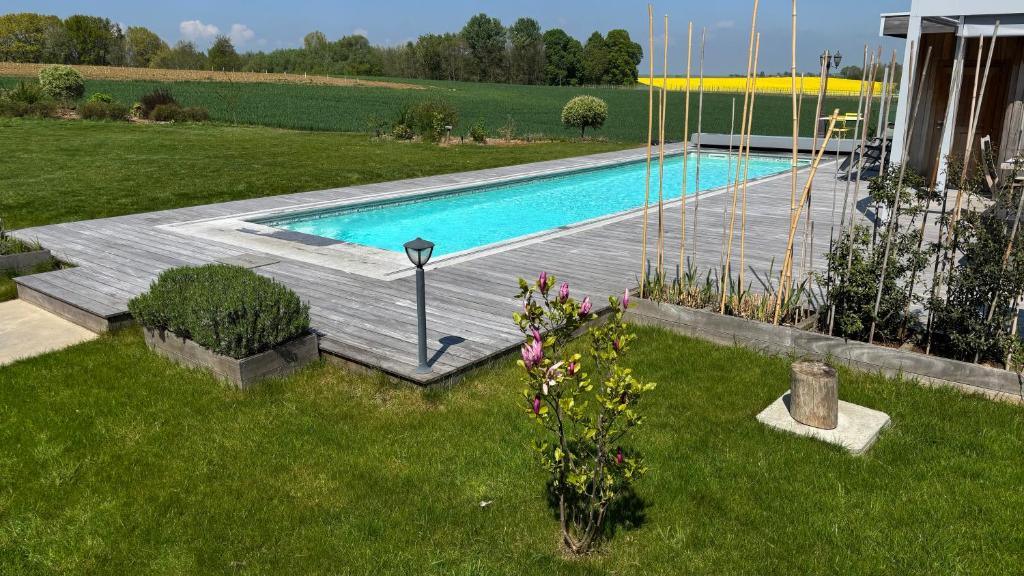 Grande piscine extérieure chauffée avec terrasse en bois et vue sur la nature