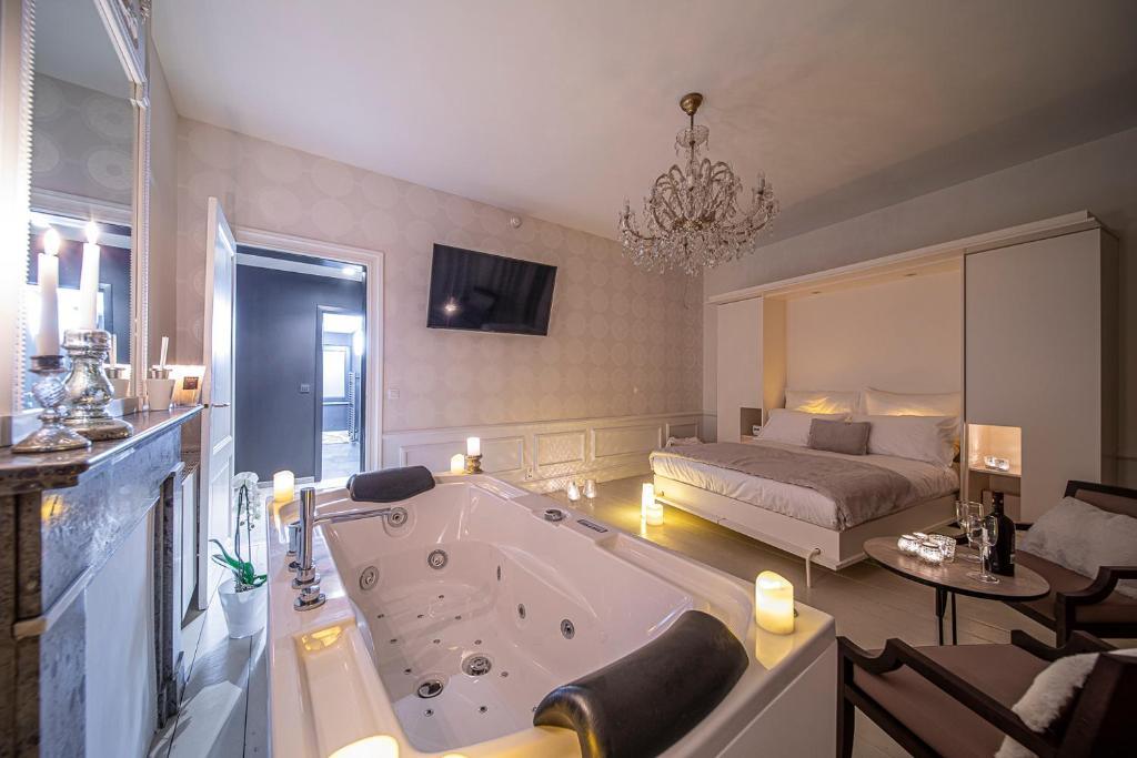 Suite romantique de luxe avec grand jacuzzi privatif au pied du lit et lustre en cristal à Liège.